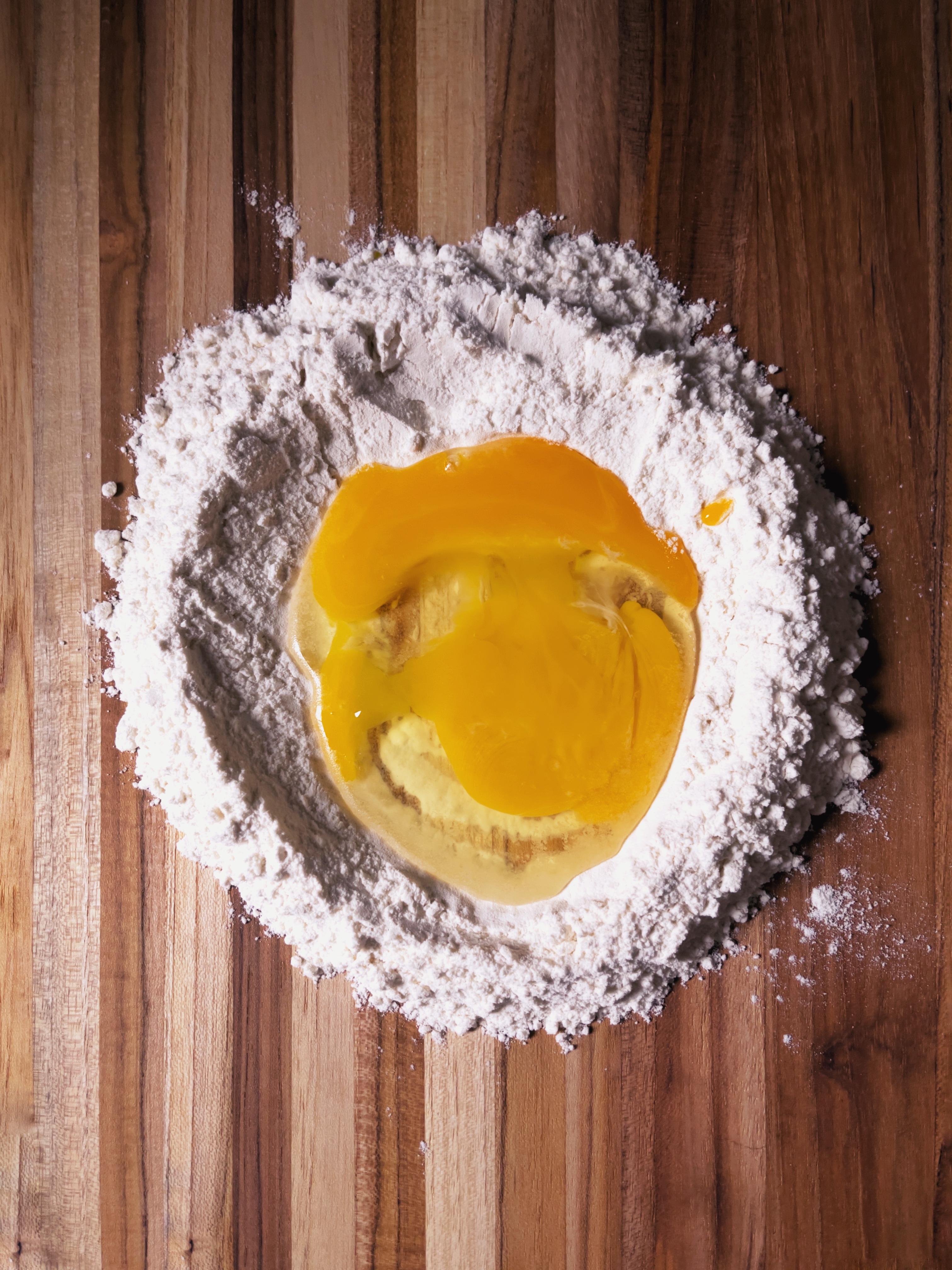 making pasta: flour and eggs on wooden board