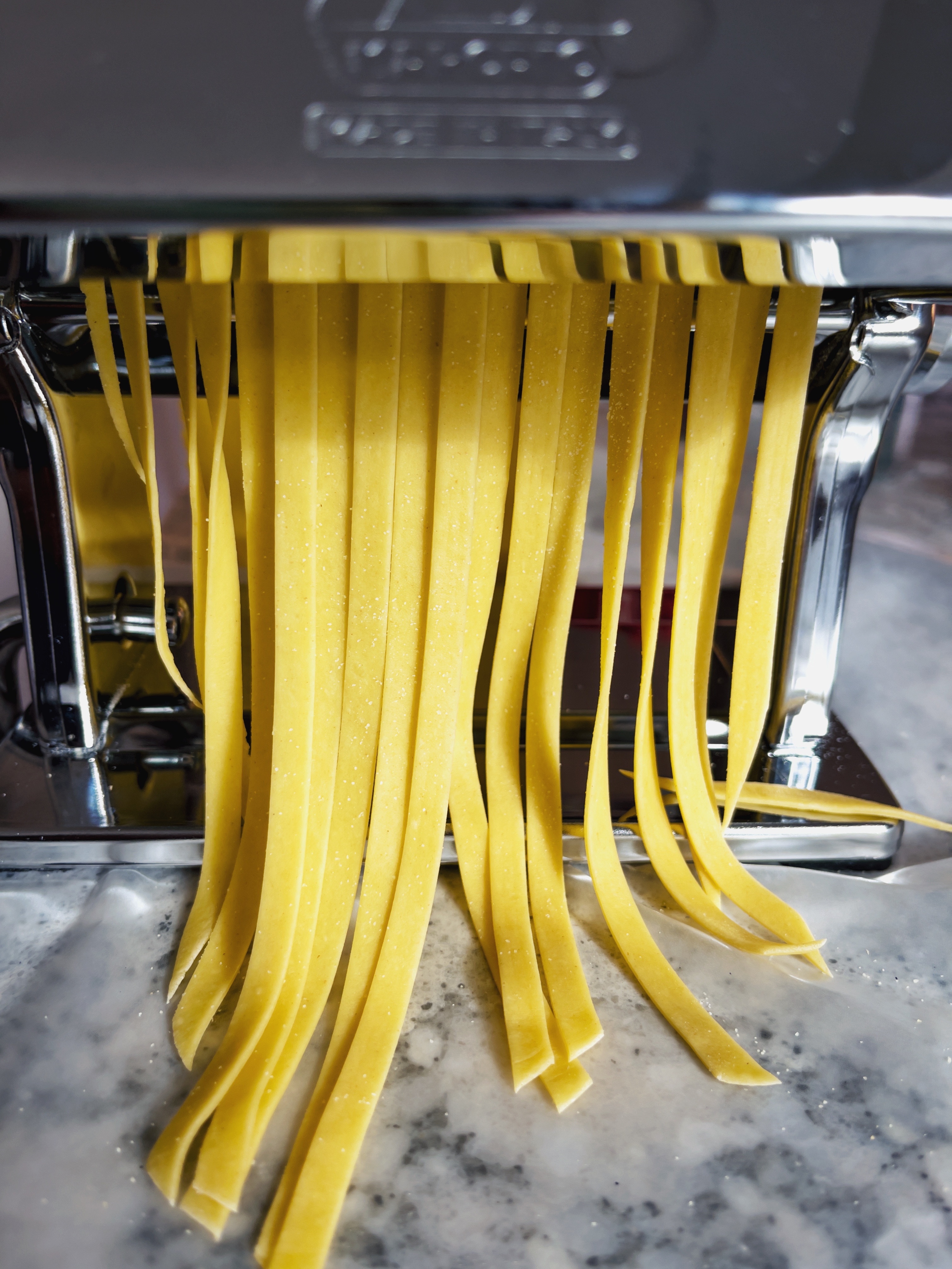 fettuccine being cut in pasta roller